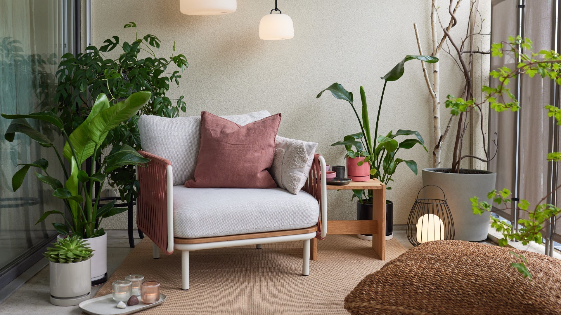 Un coin salon confortable avec un grand fauteuil, des plantes, une table d'appoint et un éclairage d'ambiance sur un balcon.