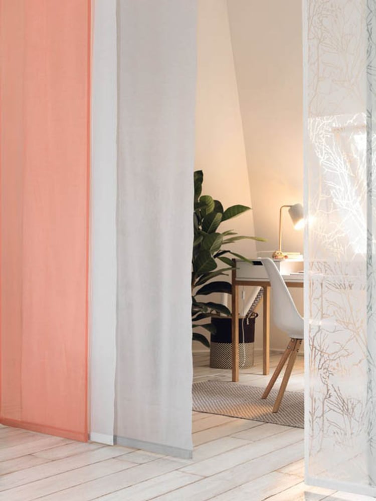 Moderne Flächenvorhänge in Pastellfarben vor einem gemütlichen Arbeitsbereich.