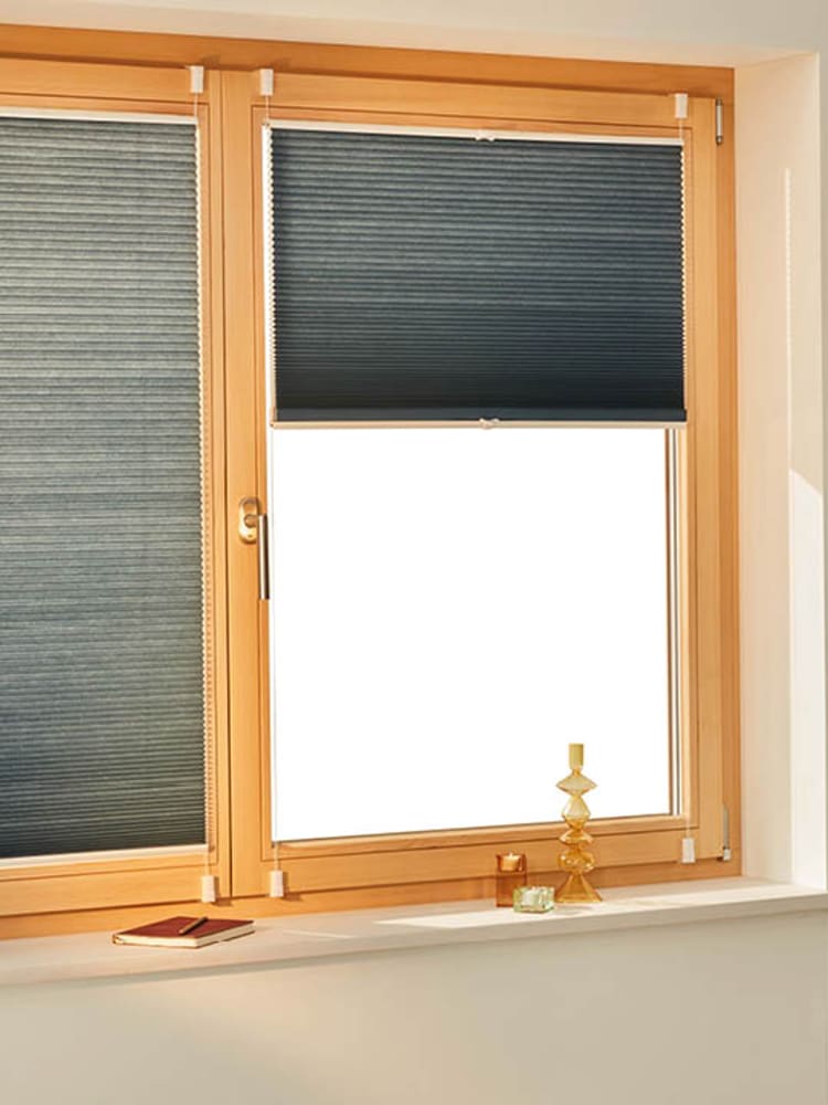 Verdunkelnde Plissees an Holzfenstern.