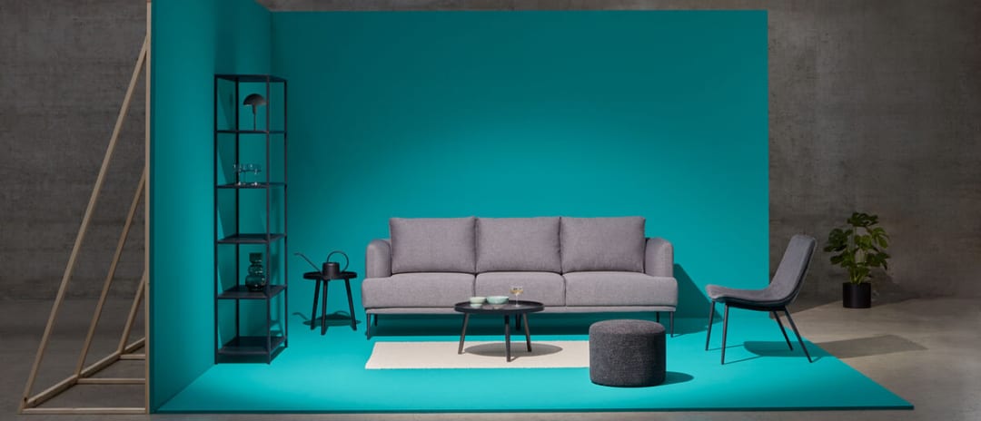 Salon avec canapé et chaise gris sur fond turquoise. Collection Budget Basics de micasa.