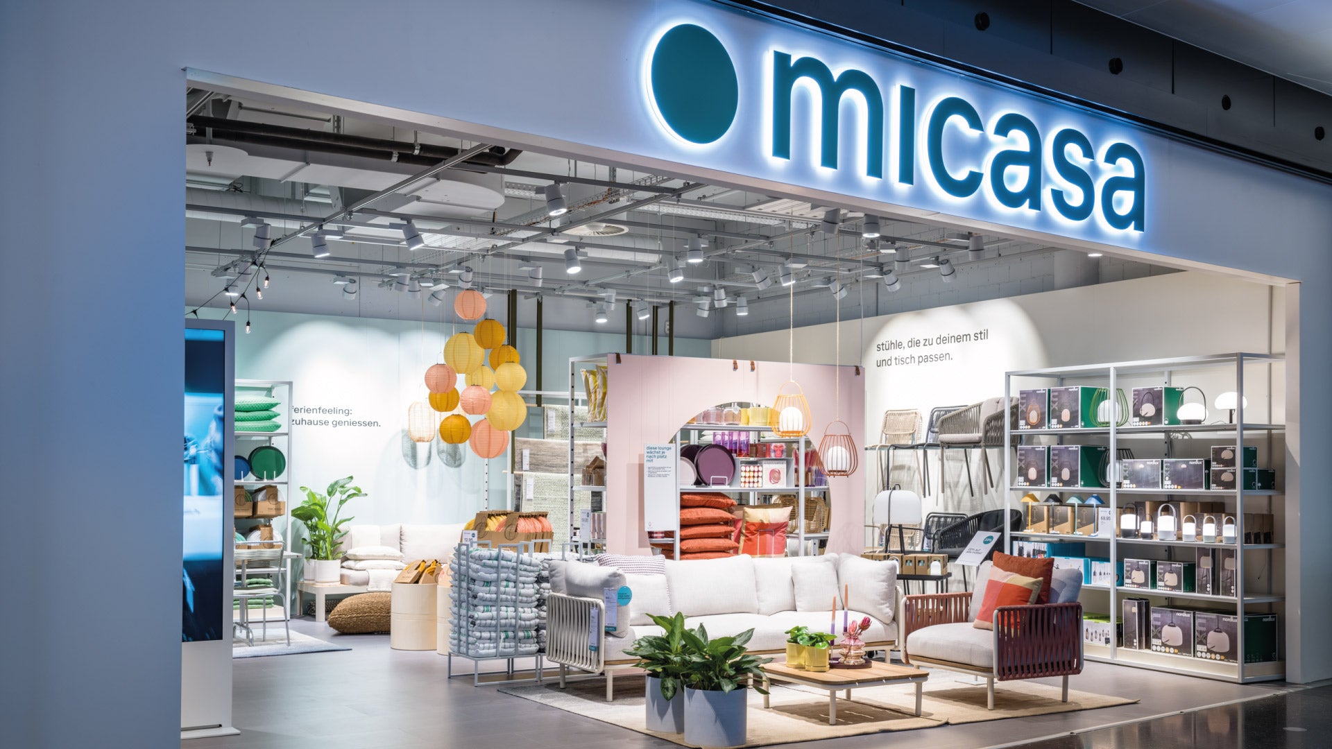 Façade du magasin Micasa avec logo lumineux et aménagement intérieur moderne.