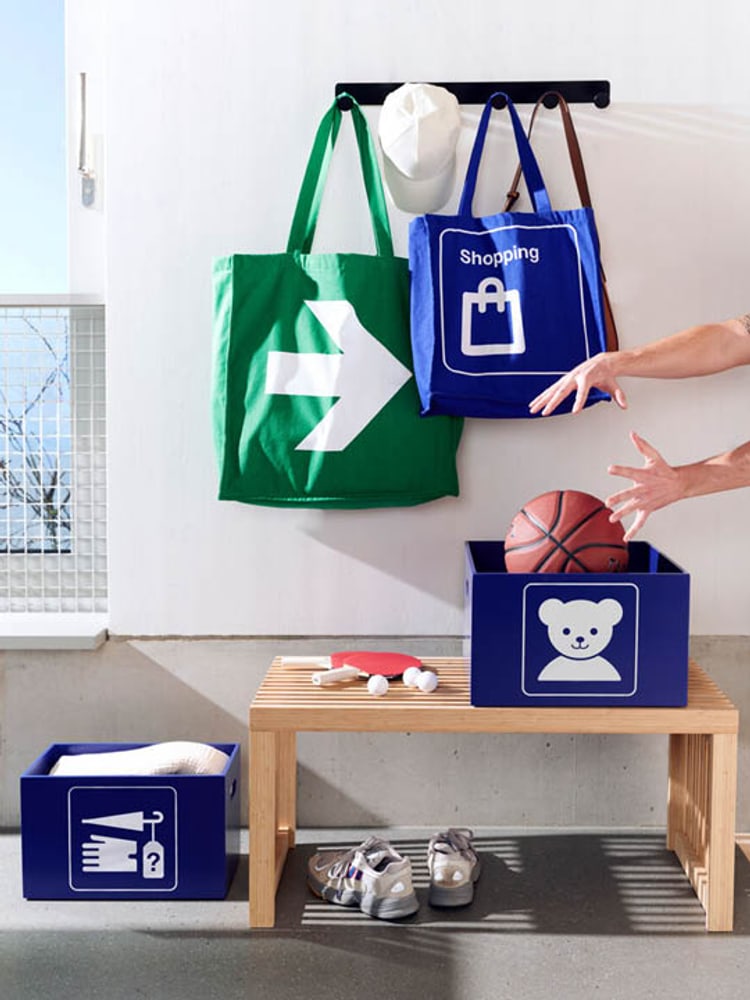 Boîtes de rangement, chaussures de sport, sacs et un ballon de basket sur un banc.
