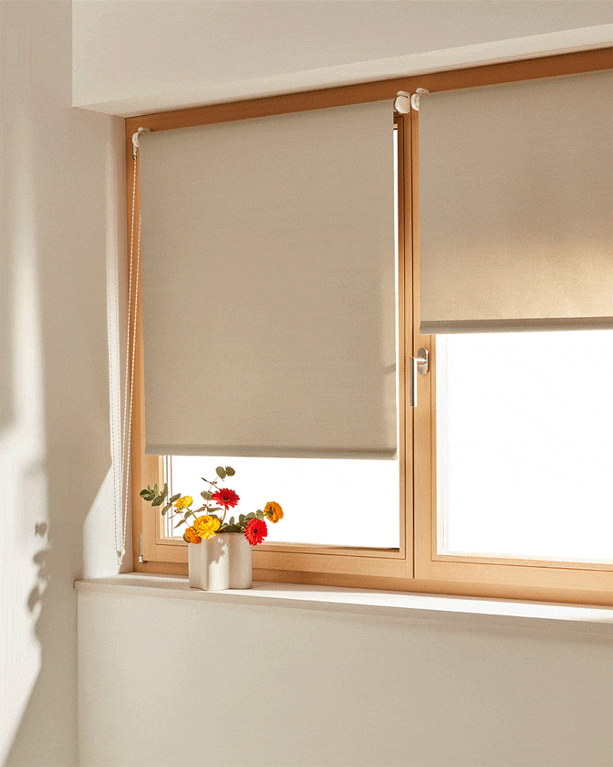 Helles Rollo an einem Fenster mit Holzrahmen.