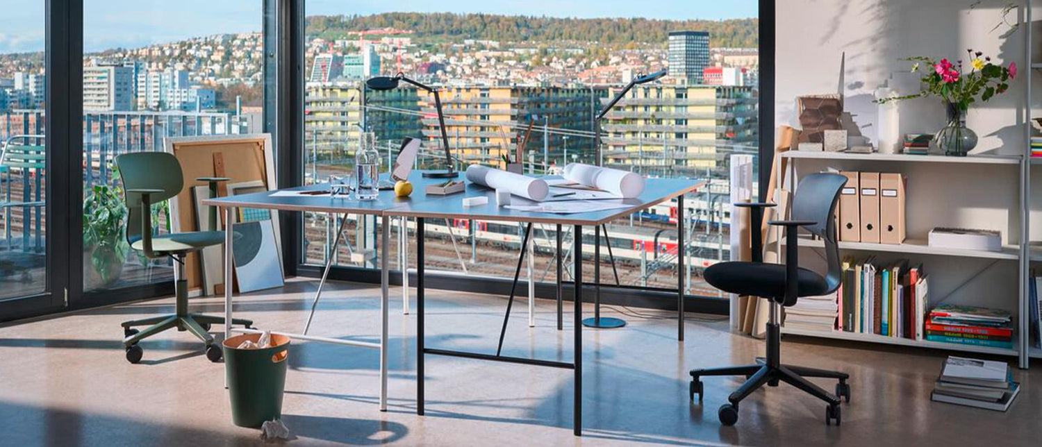 Modernes Homeoffice mit Stadtblick durch grosse Fenster. 