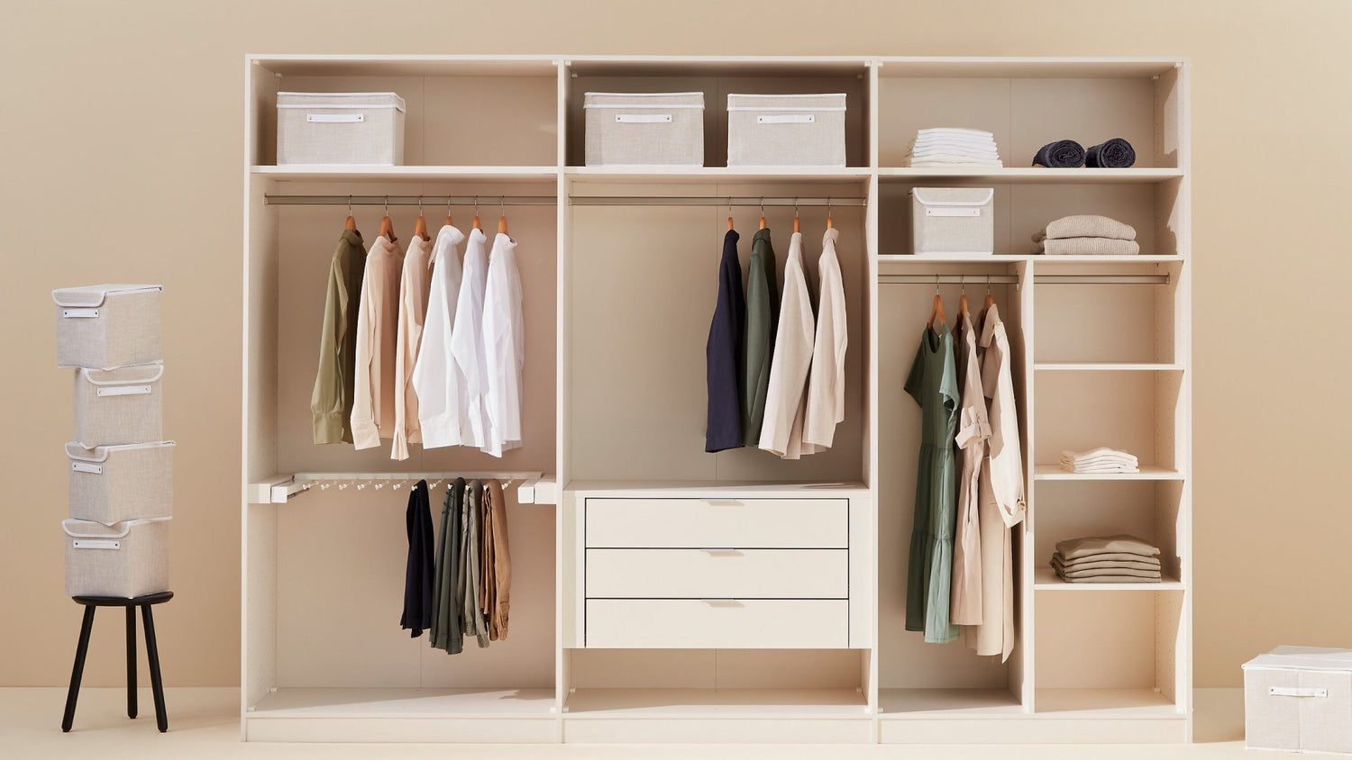 Offener, aufgeräumter Kleiderschrank mit hängender Kleidung, Schubladen, Regalfächern und Aufbewahrungsboxen in neutralen Farben.