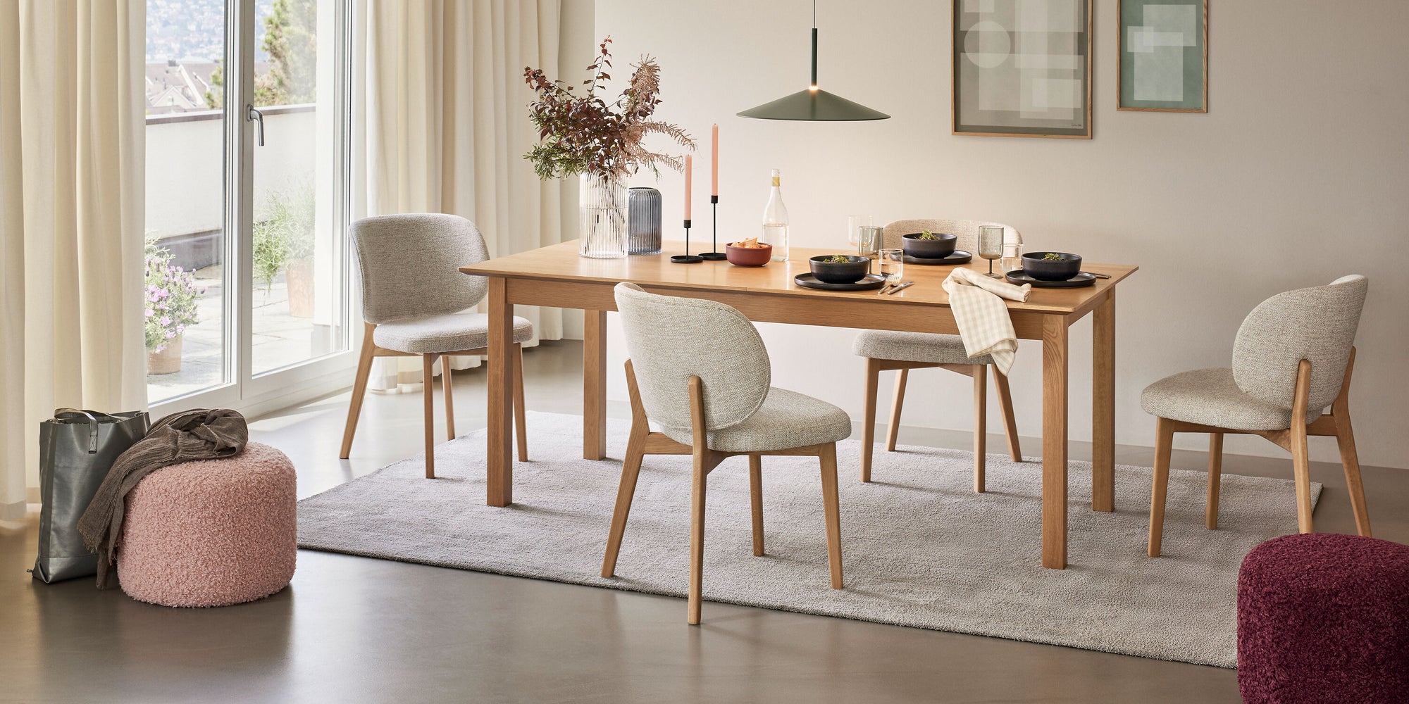 Modern eingerichtetes Esszimmer mit Holztisch, hellen Polsterstühlen, dekoriertem Gedeck und großen Fenstern mit Vorhängen.