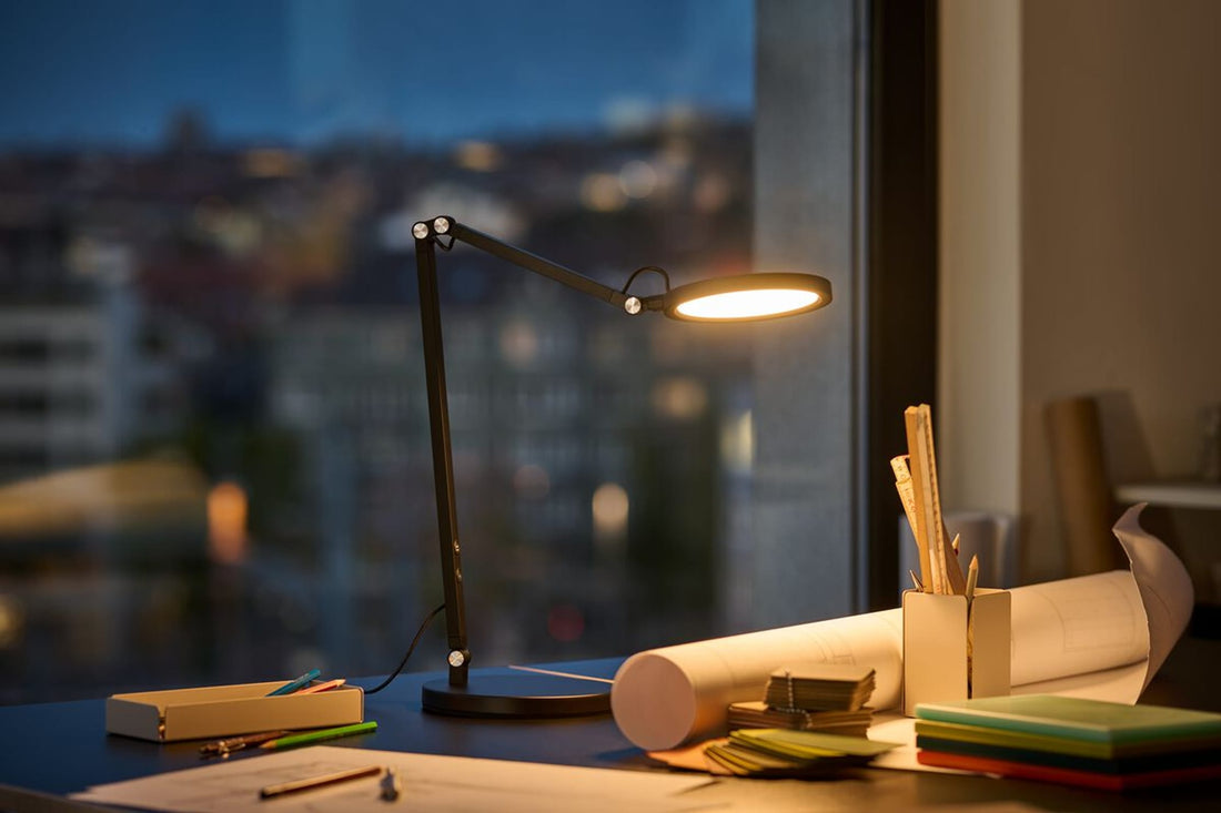 Moderne Büroleuchte erhellt Schreibtisch spätabends im Büro. 