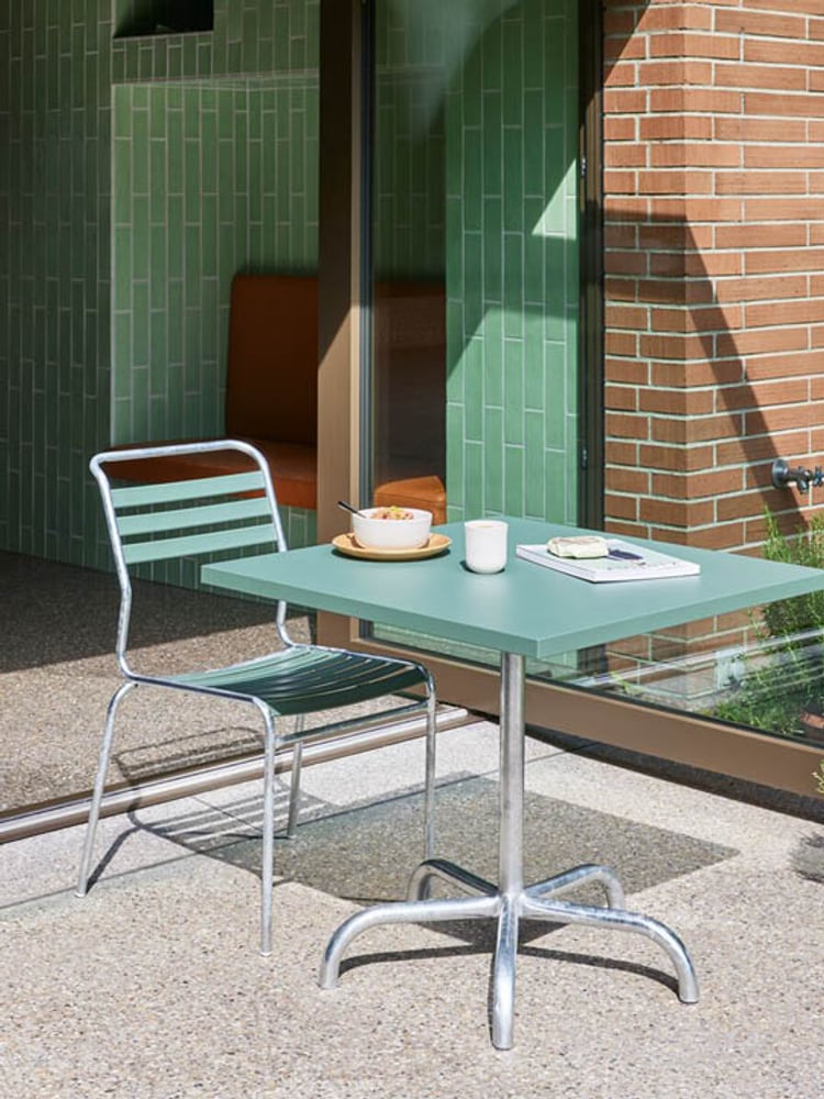 Ein grüner Tisch mit einer Tasse und einer Schale auf einer Terrasse.
