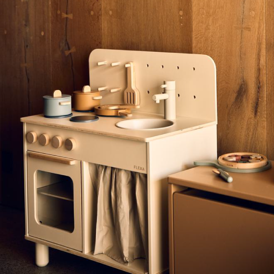 Flexa PLAY Holz-Spielküche in Hellpink mit Spüle, Herdplatten und Spielgeschirr vor einer Holzverkleidung.