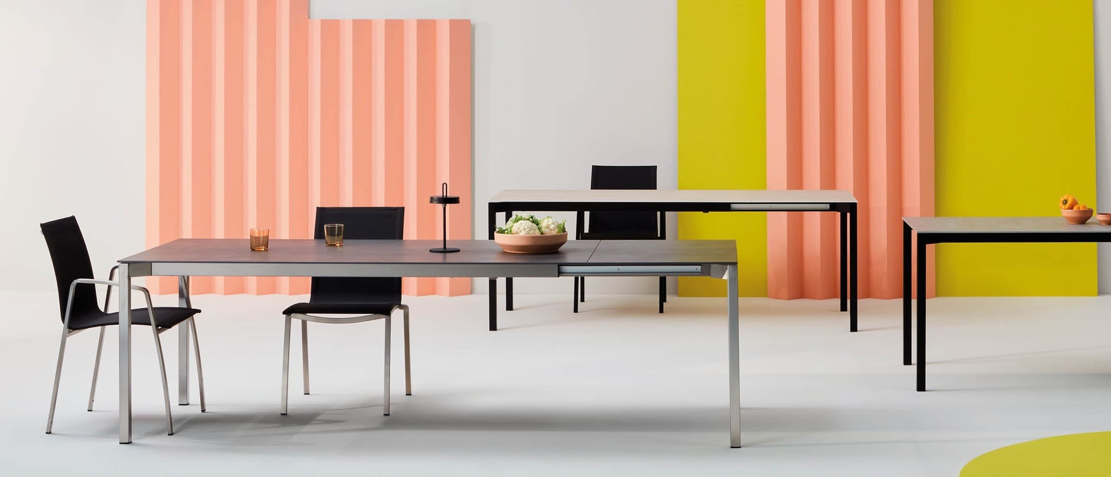 Moderne Gartentische und -stühle vor farbenfrohen Wänden.