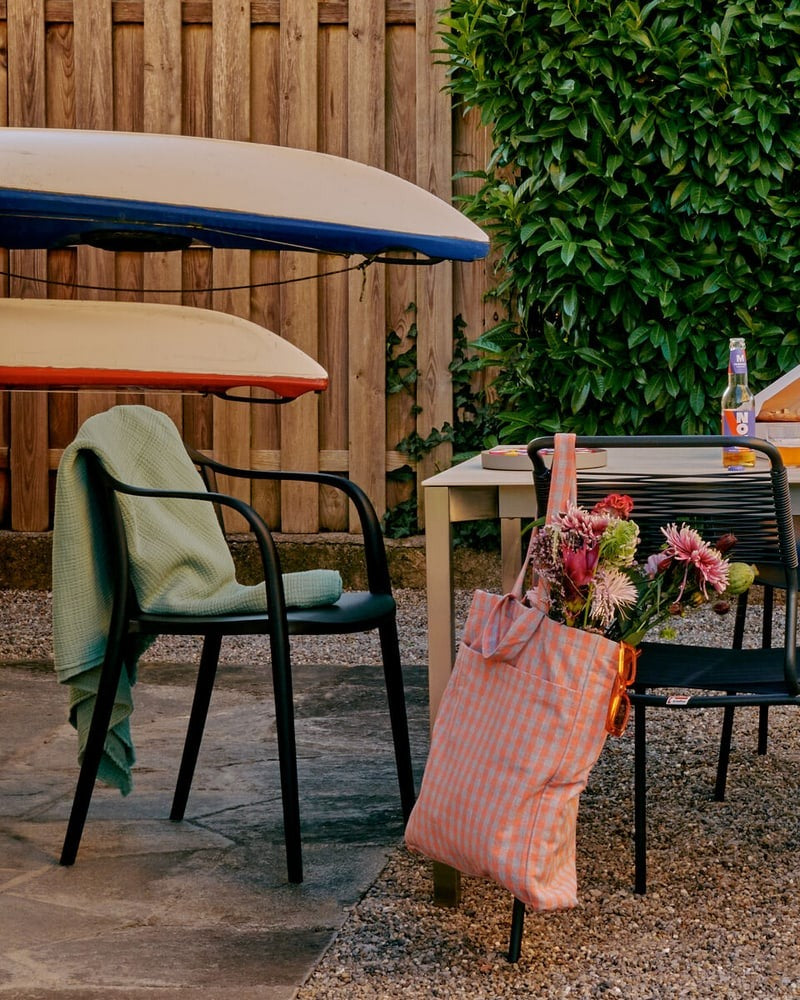 Eine gemuetliche Terrasse mit Tisch, Stuehlen, Sonnenschirm und Kajaks an der Wand.