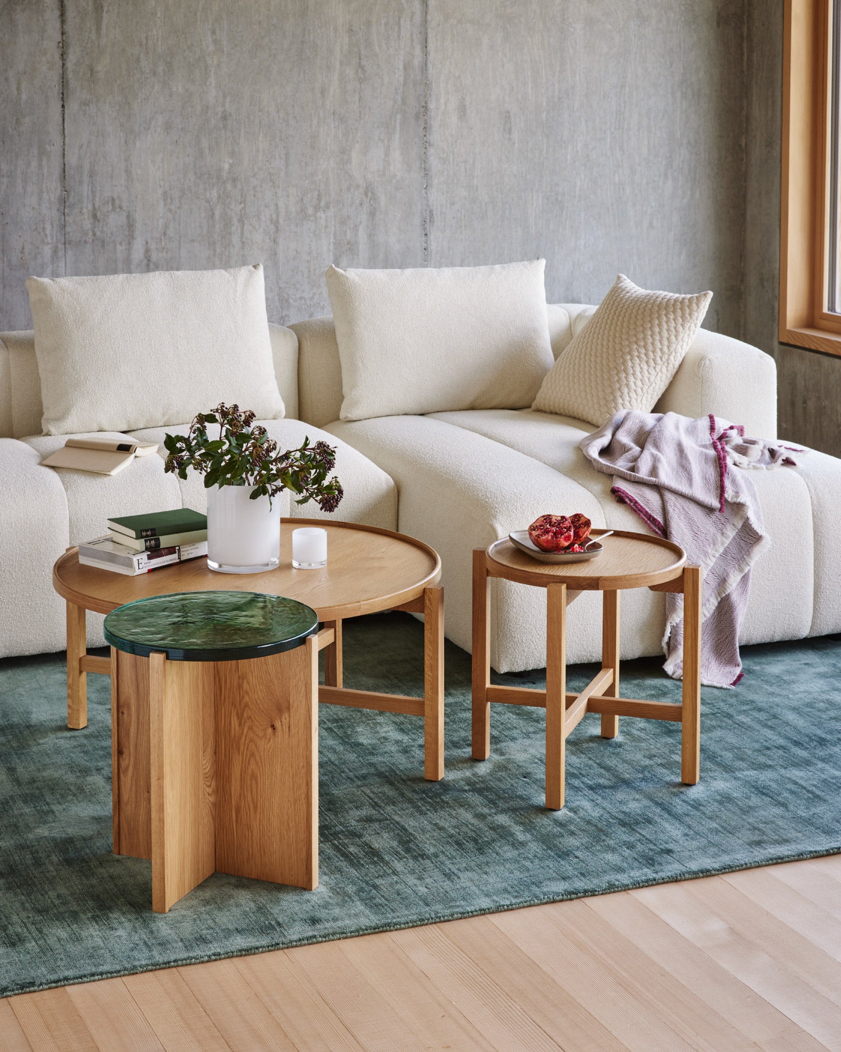 Gemütliches Wohnzimmer mit RAYAS Sofas und drei passende Salontische aus Holz.